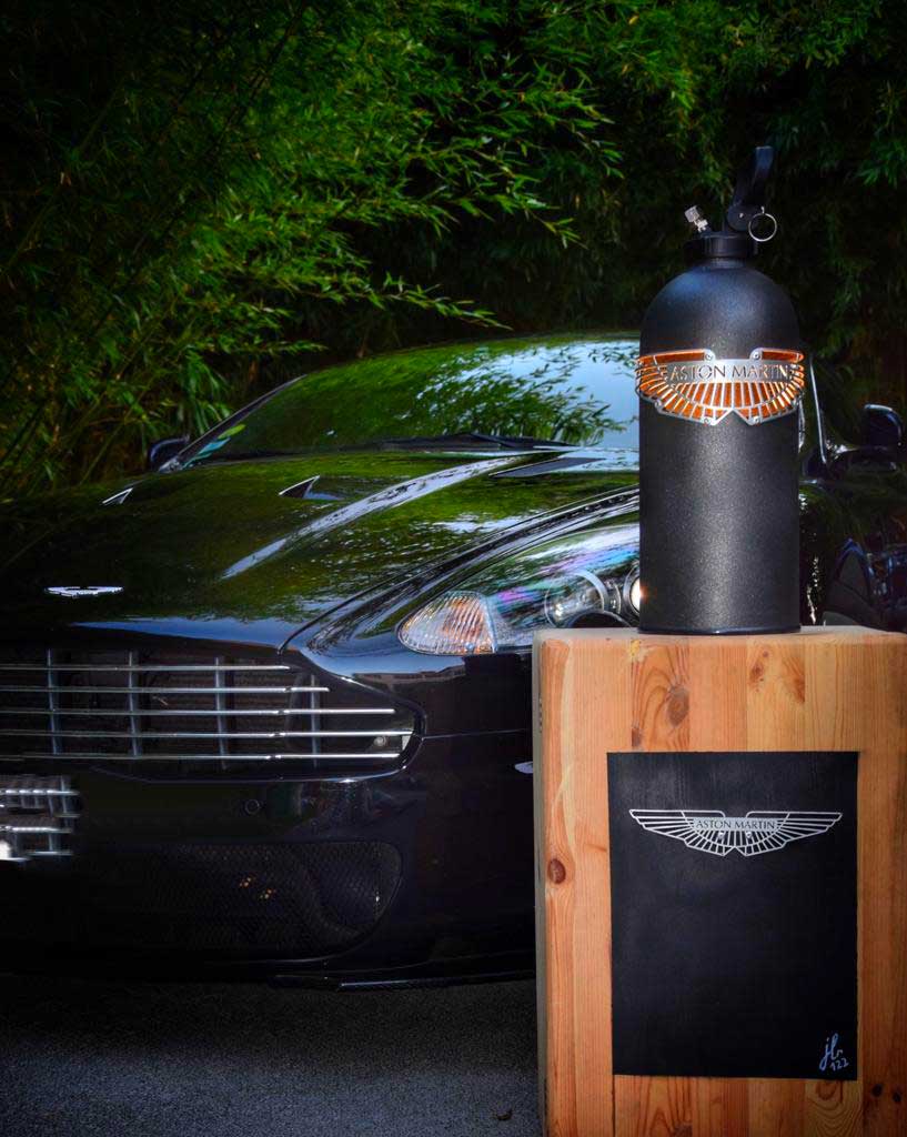 Lampe extincteur aston martin sur un socle en bois à droite d'une aston martin JLR Concept